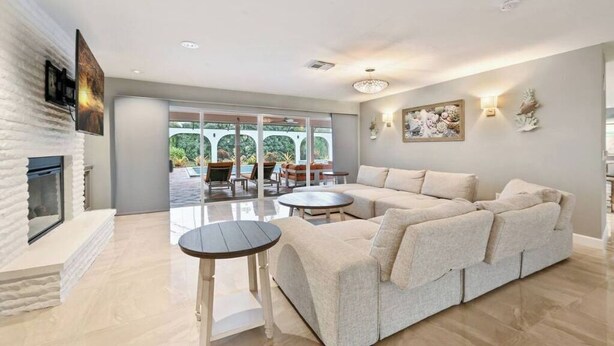 A modern living room with a fireplace, a sectional sofa, a coffee table, and a dining area with chairs. - Luxurious Naples Home. Heated Pool. Mins to Beach. (Naples)