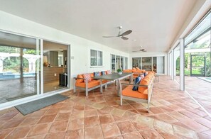 Eine geräumige Terrasse mit orangefarbener Möbel, großen Fenstern und Deckenventilatoren.