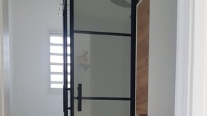 Un bagno con box doccia in vetro, mobile lavabo in legno e porta carta igienica.