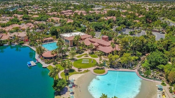 An aerial view of a resort with multiple swimming pools, a beach area, and a large building likely serving as a hotel or conference center. - Val Vista Oasis- Gorgeous Gilbert Home with Pool (Gilbert)