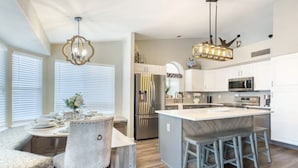 A modern kitchen with white cabinetry, stainless steel appliances, and a central island with bar stools. - Val Vista Oasis- Gorgeous Gilbert Home with Pool (Gilbert)