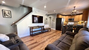 Ein modernes Wohnzimmer mit einem großen Ecksofa, einem Holztisch und einem flachen Fernseher, der an der Wand befestigt ist.