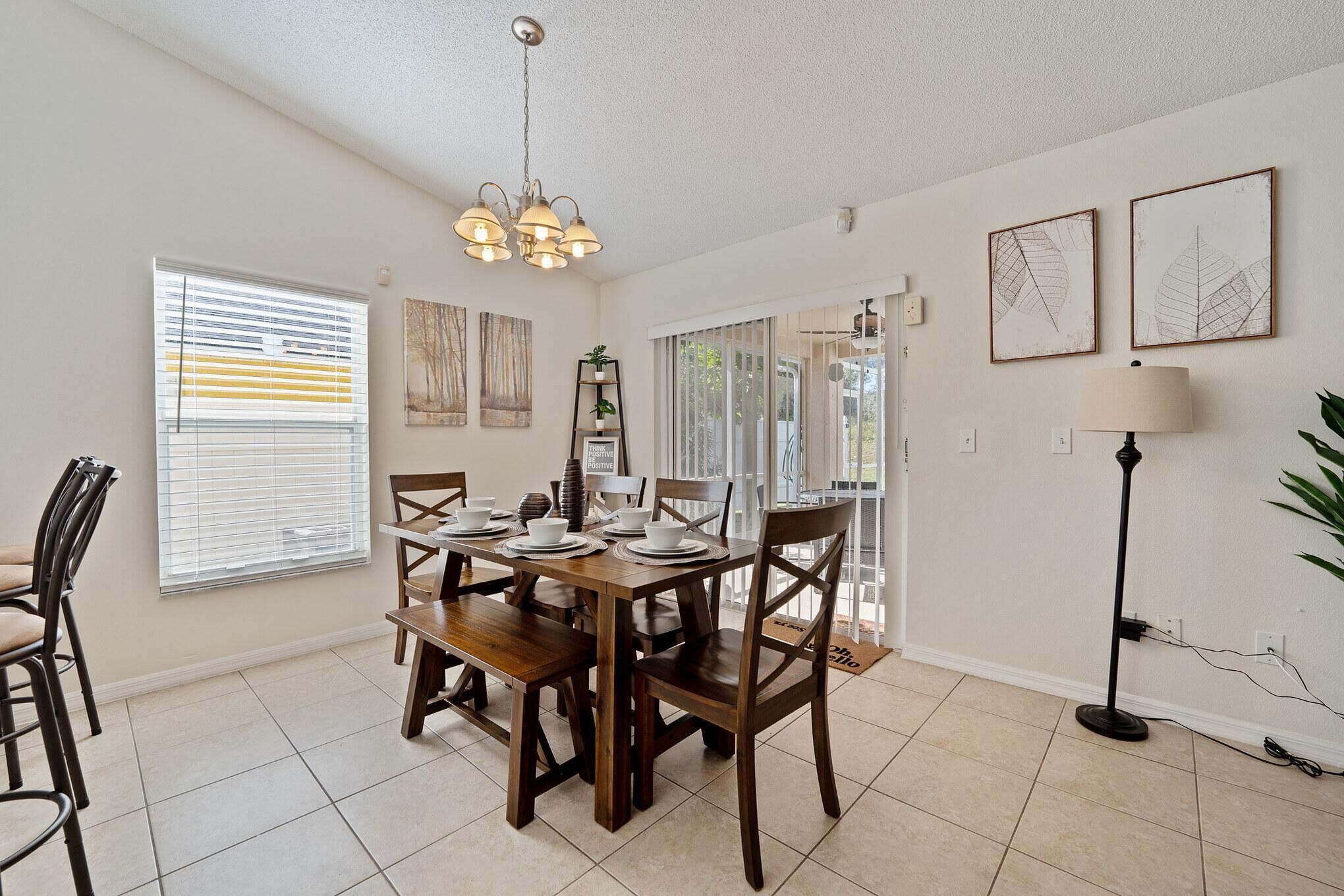 A dining area with a wooden table set for four, a chandelier, and artwork on the walls.