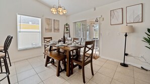 A dining area with a wooden table set for four, a chandelier, and artwork on the walls.