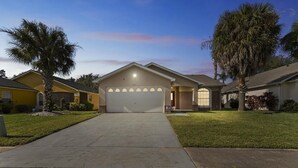 A residential house with a garage, two palm trees, and a well-maintained lawn.
