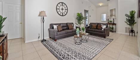 Un salon spacieux avec deux canapés, une table basse et un tapis à motifs.