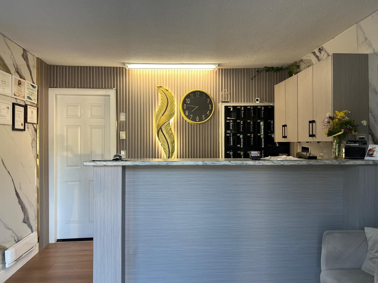 A modern kitchen with a built-in clock, a wooden cabinet, and a white door.