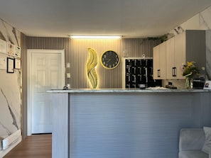 A modern kitchen with a built-in clock, a wooden cabinet, and a white door.