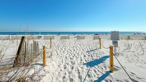 En sandstrand med ett trästaket och en skylt som visar var man får lämna sitt avfall.