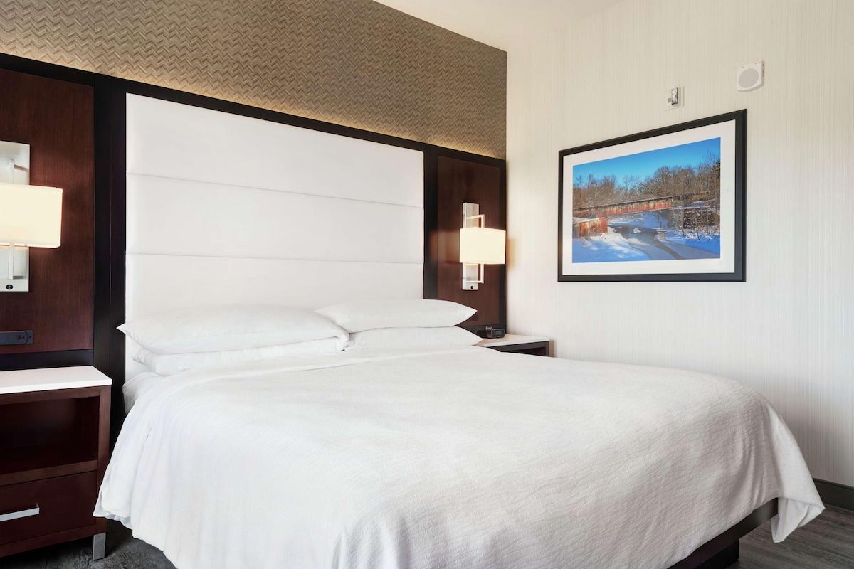 Una cama bien hecha en una habitación de hotel, con un cuadro grande en la pared.