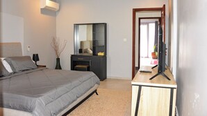 Une chambre à coucher comprenant un lit, un bureau avec un ordinateur, un miroir et un appareil de climatisation.