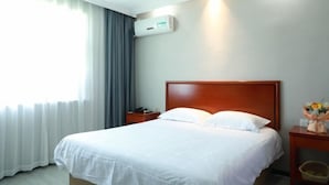 A hotel room with a large bed, a nightstand, a wall-mounted air conditioner, and a window with curtains. - Shell Hotel (Suzhou Yangcheng Lake Peninsula Yangcheng Peninsula Park)‌ (Suzhou)