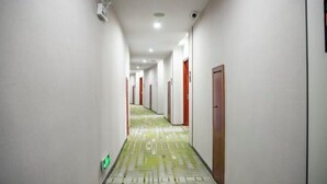 A long, narrow hallway with doors on both sides, a patterned floor, and a security camera on the ceiling. - Shell Hotel (Suzhou Yangcheng Lake Peninsula Yangcheng Peninsula Park)‌ (Suzhou)