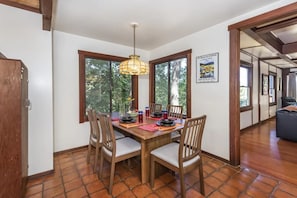 A dining area with a wooden table, chairs, and a hanging light fixture.