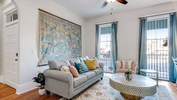 A living room with a grey sofa, a round coffee table, and a large floral painting on the wall.