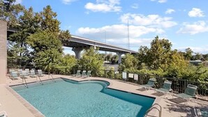 A swimming pool with lounge chairs and a bridge in the background. - Nash Riverfront Condo, Sleeps 6, Walk to Broadway (Nashville)