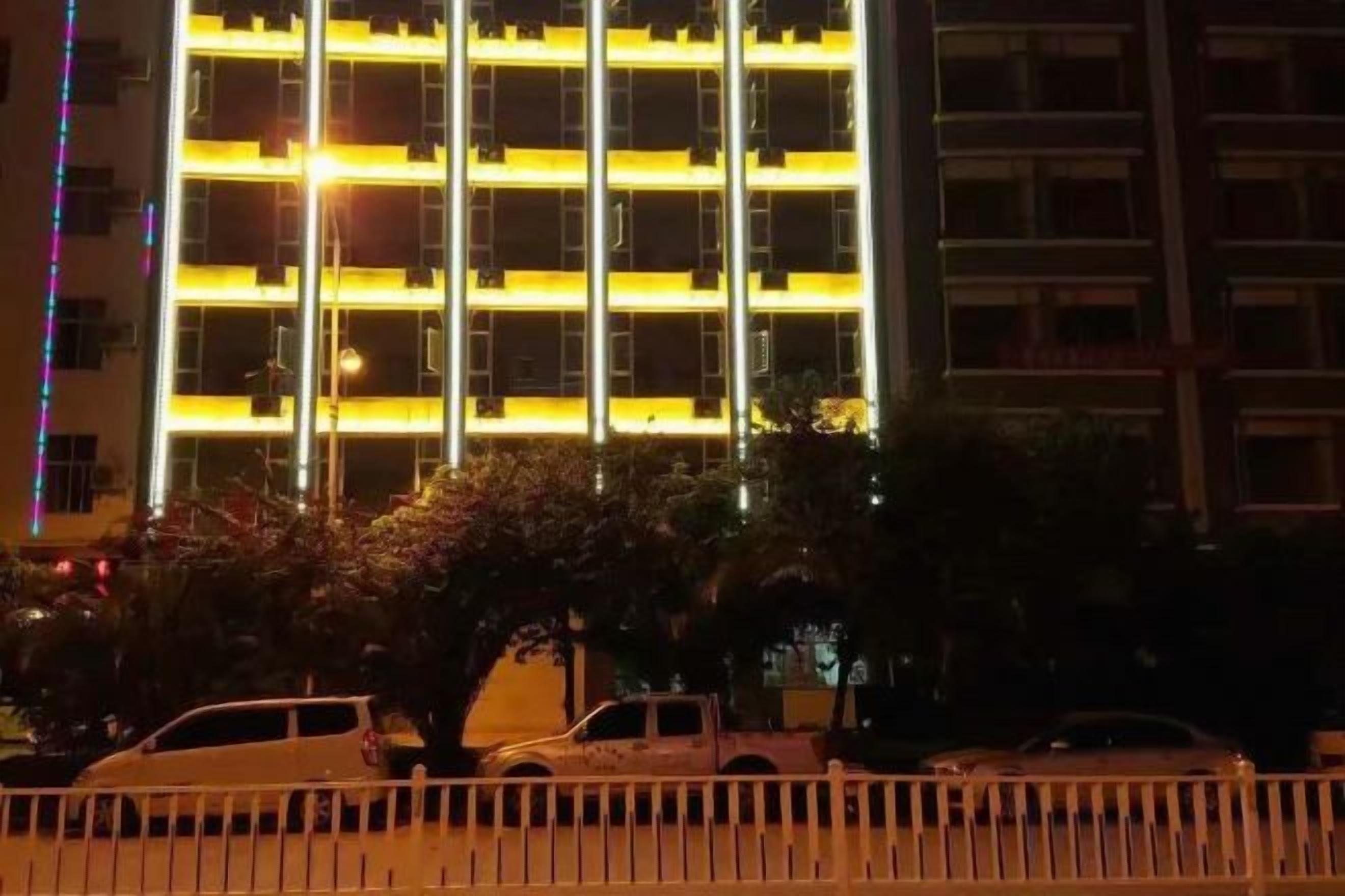 A multi-story building with a grid-like facade, likely a hotel or office building, with a parking area in the foreground.