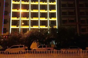 A multi-story building with a grid-like facade, likely a hotel or office building, with a parking area in the foreground. - Bandao Hotel (Binchuan)