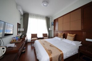 A hotel room with a large bed, a desk with a chair, a TV, and a window with curtains.