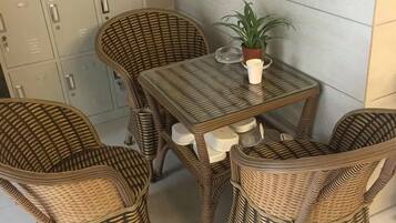 Ein Korbspeiseset mit Tisch und vier Stühlen, ein Blumentopf und eine wandmontierte Schrank.