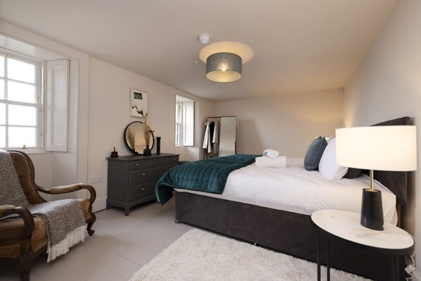 A bedroom with a bed, a chair, a dresser, a mirror, and a lamp. - Observatory Apartment at Calton Hill (Edinburgh)