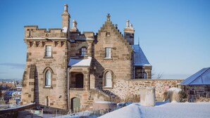A historic stone building with multiple chimneys, a central arched entrance, and a staircase leading to the main entrance. - Observatory Apartment at Calton Hill (Edinburgh)