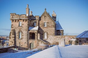 A historic stone building with multiple chimneys, a central arched entrance, and a staircase leading to the main entrance. - Observatory Apartment at Calton Hill (Edinburgh)
