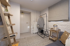 A modern bedroom with a bed, a wooden ladder, a radiator, a hanging clothes rack, and a bedside table with a lamp. - Observatory Apartment at Calton Hill (Edinburgh)