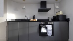 A modern kitchen with a built-in oven, a microwave, and a stainless steel countertop. - Observatory Apartment at Calton Hill (Edinburgh)