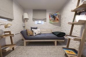 A small, cozy room with a single bed, a lamp, a bookshelf, and a poster on the wall.