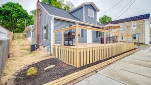 Une maison avec une terrasse en bois et un barbecue.