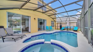 Una piscina interior con bordes de azulejos azules, rodeada de sillas de descanso y un patio cubierto.