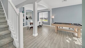 Amplia sala de estar con mesa de billar, comedor y cocina equipada con alacenas y microondas.