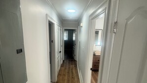 A hallway with wooden flooring, white walls, and doors leading to other rooms. - Chill & Relax 3bd (Marietta)