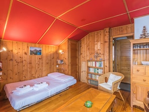 A wooden room with a bed, a bookshelf, a wicker chair, and a wooden cabinet. - Chalet Bossons  - Welkeys (Chamonix-Mont-Blanc)
