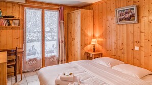 A wooden room with a bed, a desk, and a window with curtains. - Chalet Bossons  - Welkeys (Chamonix-Mont-Blanc)