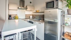 Una cocina moderna con electrodomésticos de acero inoxidable, una encimera blanca y una planta en maceta.