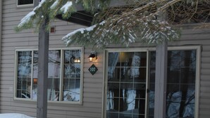 Une maison dont la cour avant est recouverte de neige, avec de grandes fenêtres et un panneau indiquant le numéro de la maison.
