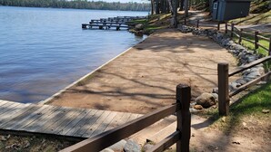 Une jetée en bois s’étendant dans un lac paisible, entourée d’un mur de pierre et d’une clôture en bois.