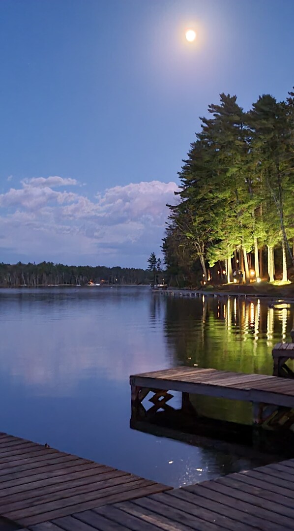 Un lac paisible au crépuscule, avec une jetée en bois qui s’avance sur l’eau.