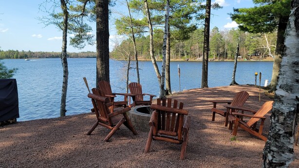 Un espace aménagé au bord du lac, avec des fauteuils Adirondack et un foyer.
