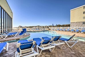 Ett poolområde med solstolar och utsikt över havet.
