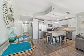 A modern kitchen with white cabinets, stainless steel appliances, and a central island with stools.