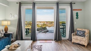 En stue med udsigt til en balkon, en sofa, et sofabord og en lampe.