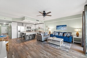 A modern living room with a sofa, coffee table, and a dining area with a table and chairs.