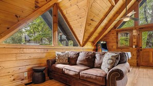 A wooden interior with a leather sofa, wooden walls, and large windows. - Scenic Mtn View Cabin with Hot Tub (Seveirville)