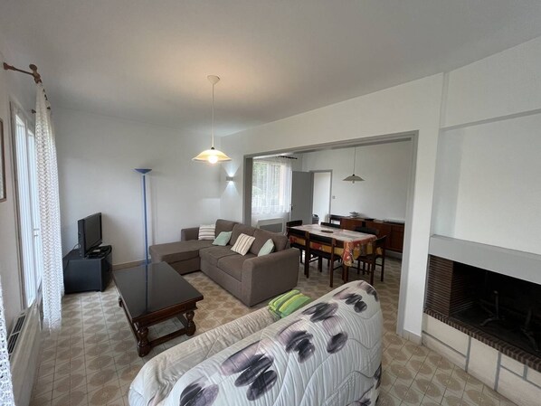 A living room with a sofa, a coffee table, a TV, and a fireplace.
