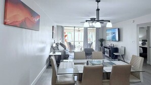 Un saló modern amb zona de menjador, televisió penjada a la paret i un quadre gran.