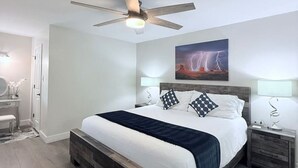 Une chambre à coucher avec un lit en bois, un ventilateur de plafond, une table de chevet et une lampe fixée au mur.