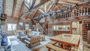 A log cabin interior with a dining area, seating, and a staircase.